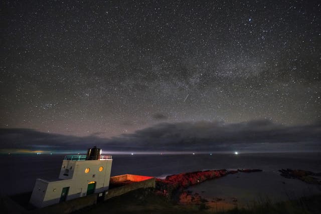 <p>The Milky Way core rises at 3am over Bamburgh Lighthouse in Northumberland on the North East (Owen Humphreys/PA)</p>
