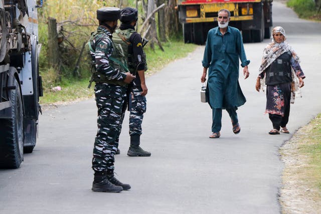 <p>Indian army soldiers stand guard as Kashmiri residents walk past</p>