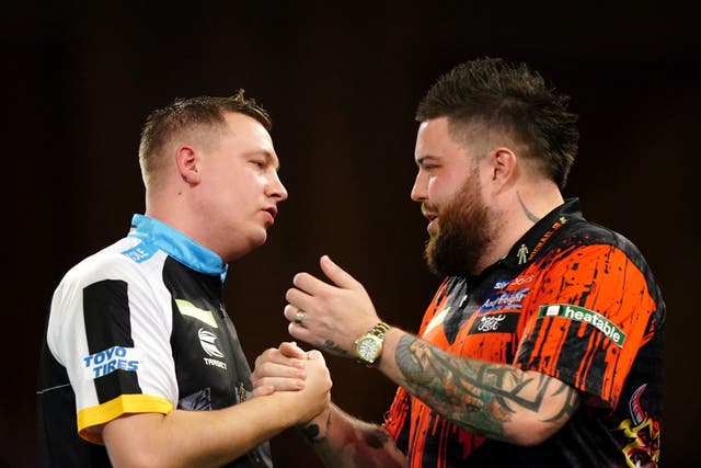 <p>Chris Dobey embraces Michael Smith after defeating the 2023 champion</p>